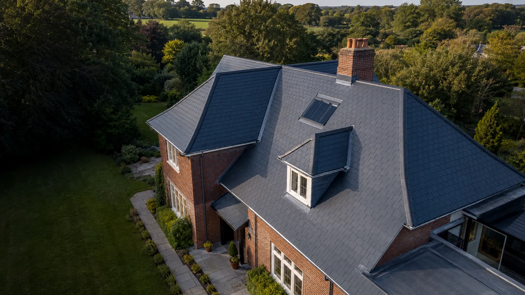Aerial view of a large detached house with a newly finished natural slate roof by Tammat Group